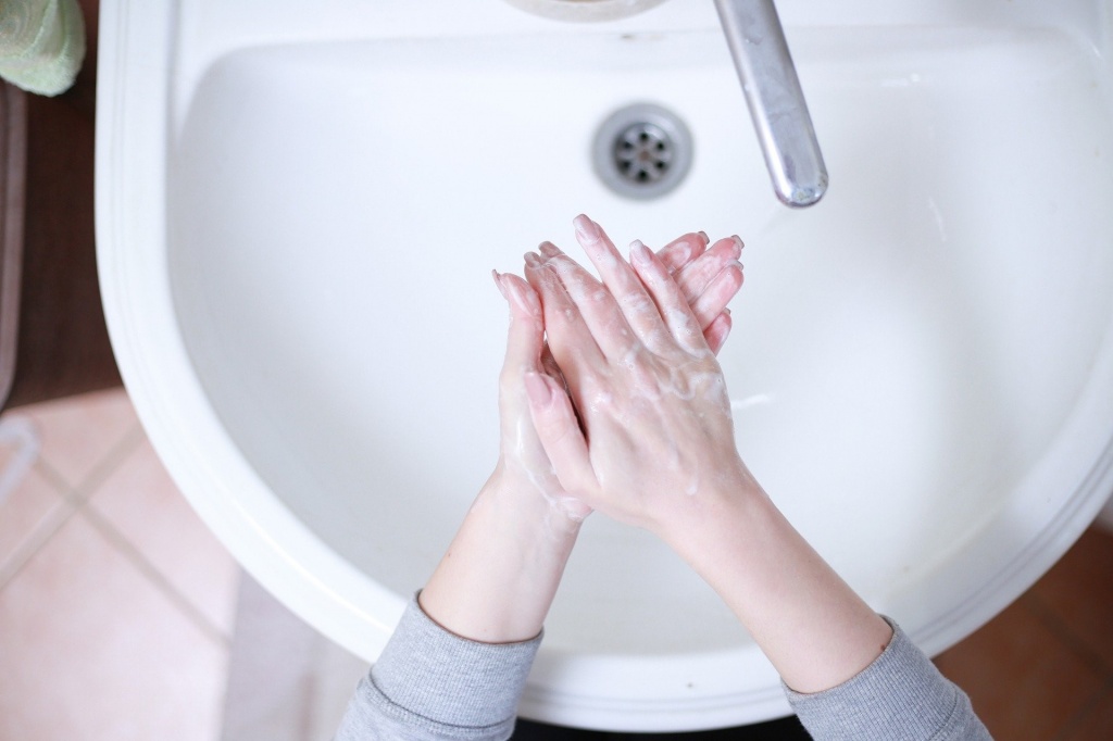 Женщина моет руки над раковиной