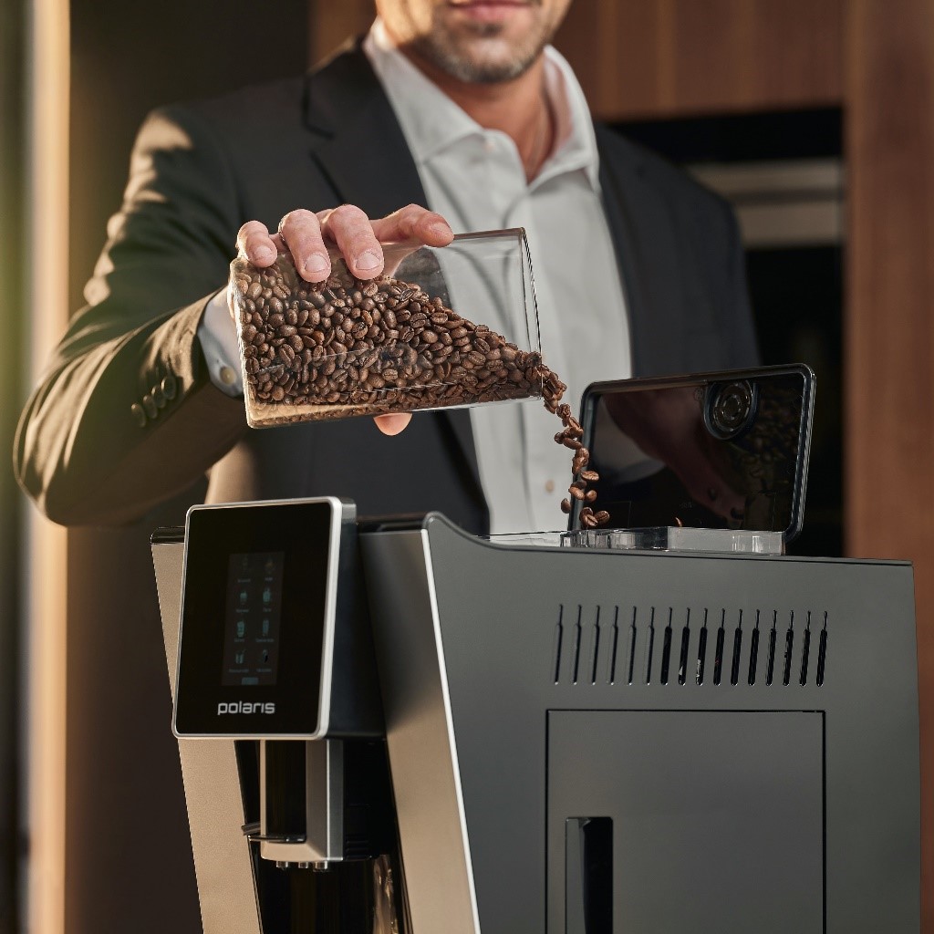 Мужчина засыпает кофейные зерна в автоматическую кофемашину Polaris